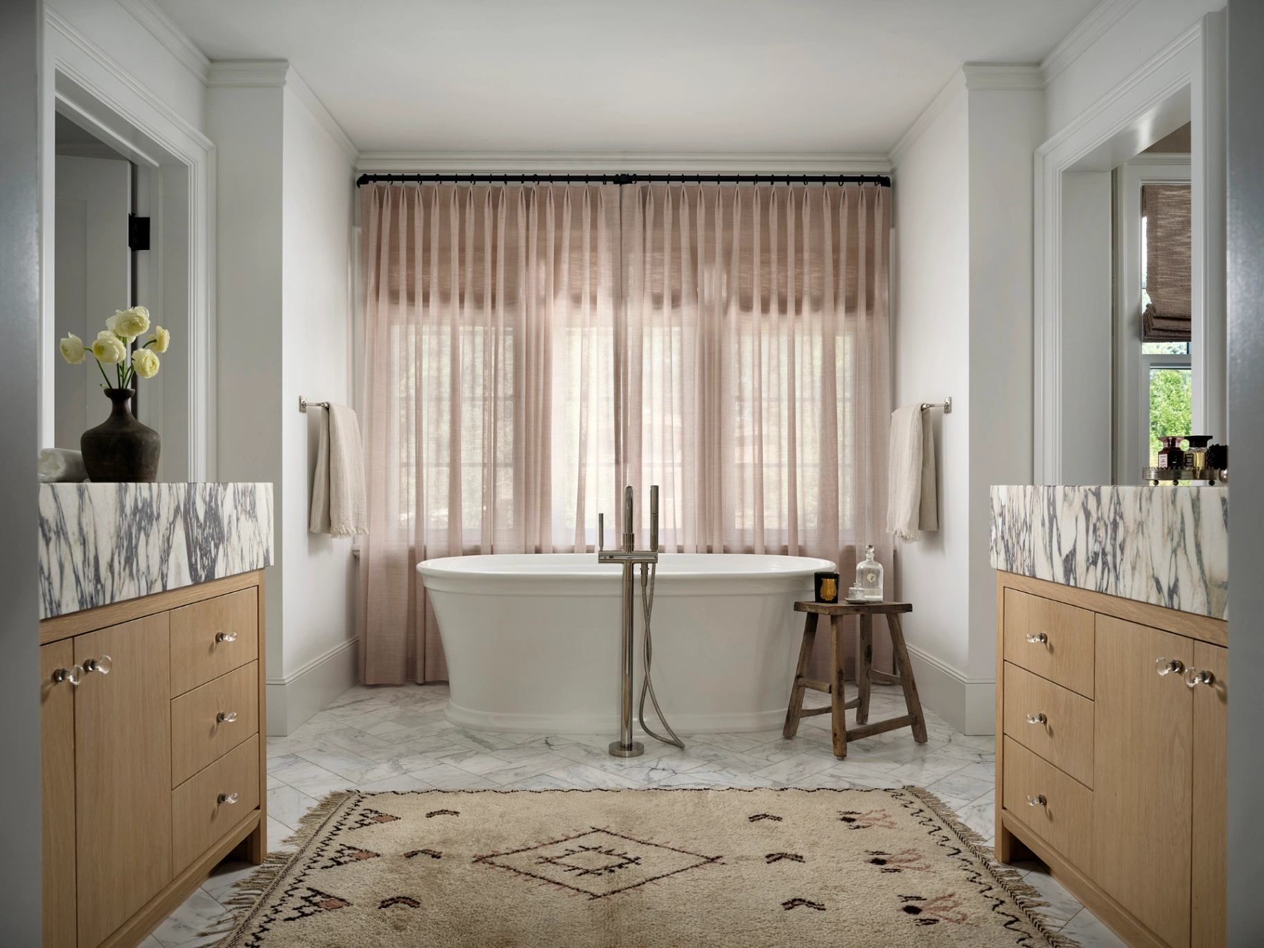 Custom sheer linen drapery panels framing a freestanding tub in a luxurious primary bathroom