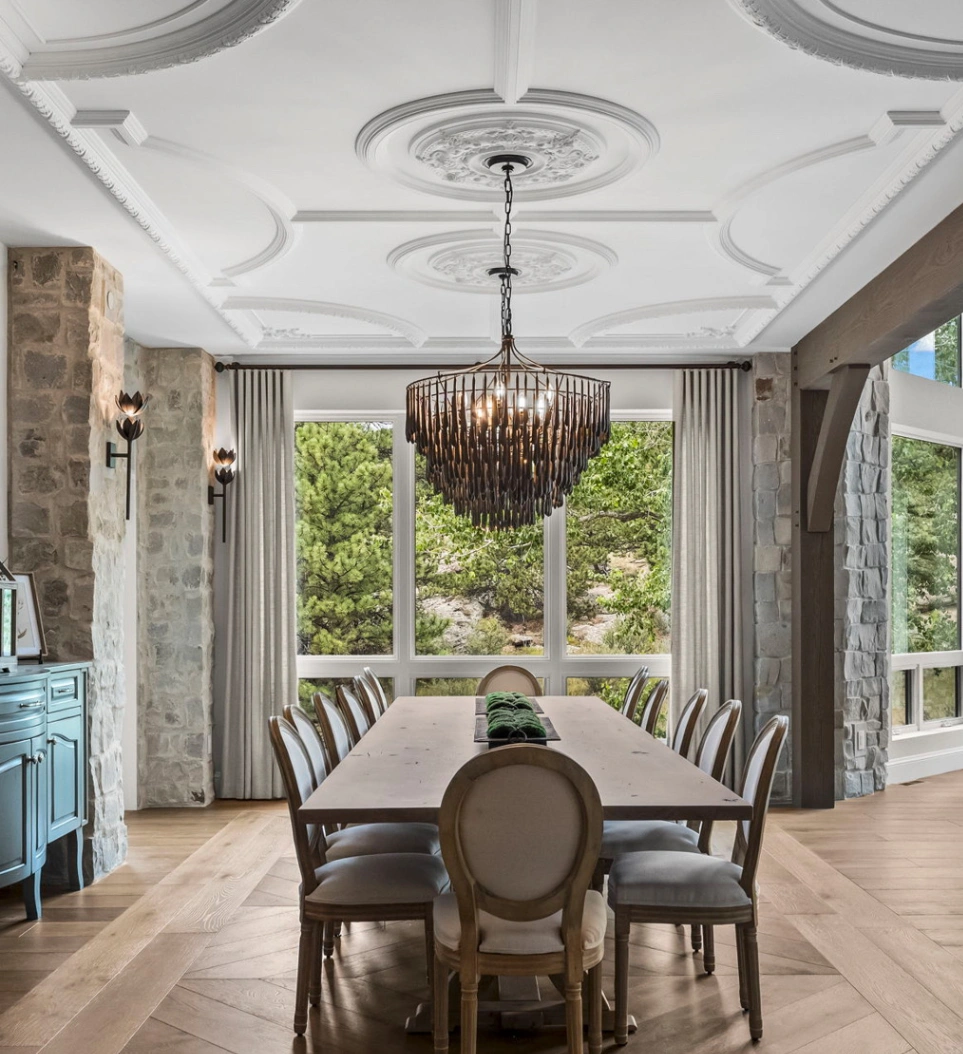 Bespoke gray linen drapery panels framing a breathtaking wooded view in a grand stone dining room