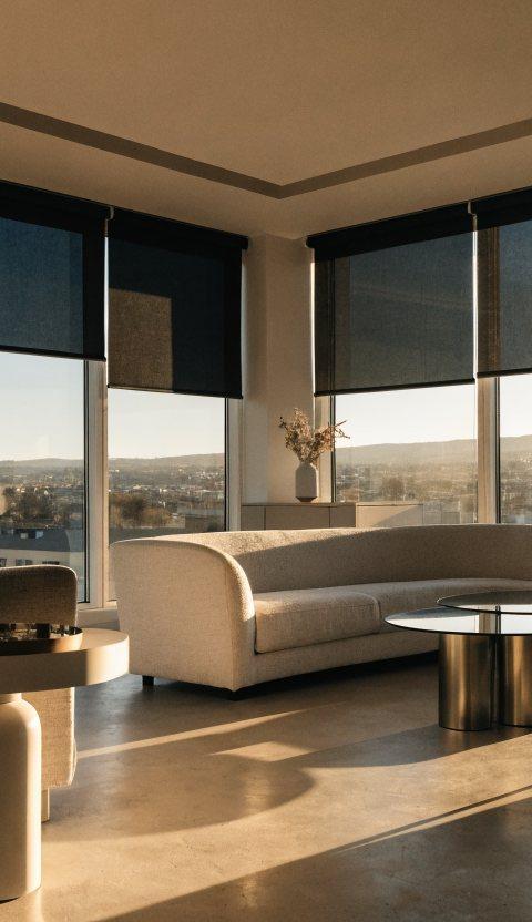 Sleek motorized roller shades at varying heights on a wall of windows in a modern Denver great room