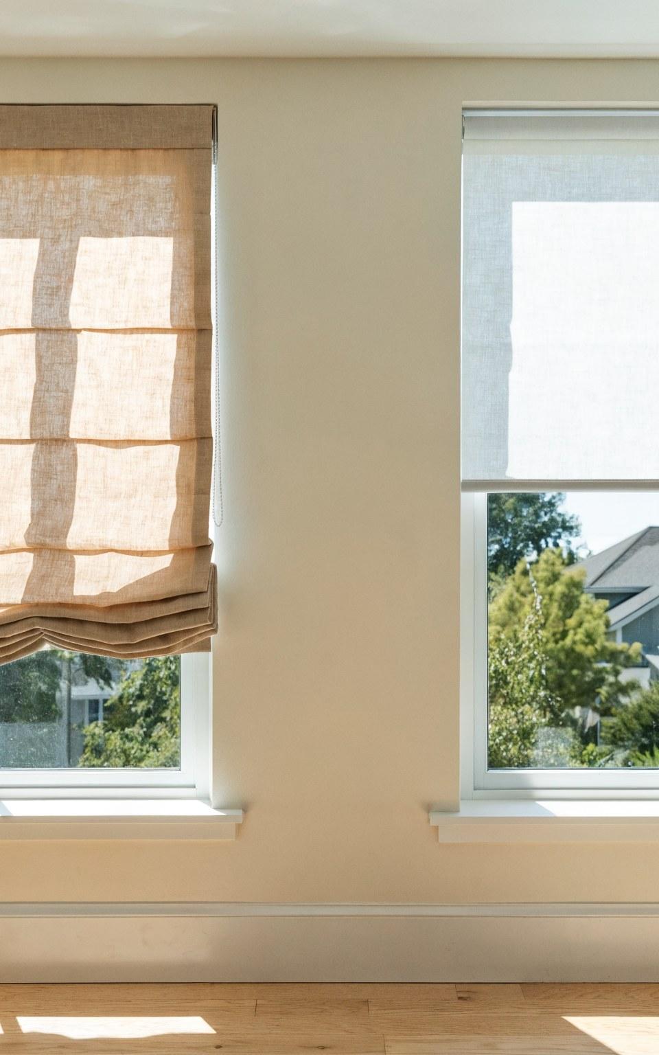 Side by side comparison of a soft Roman shade and a sleek roller shade on adjacent windows in a bright Denver home