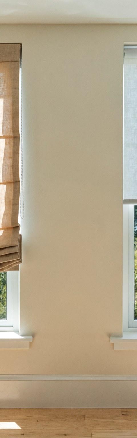 Side by side comparison of a soft Roman shade and a sleek roller shade on adjacent windows in a bright Denver home