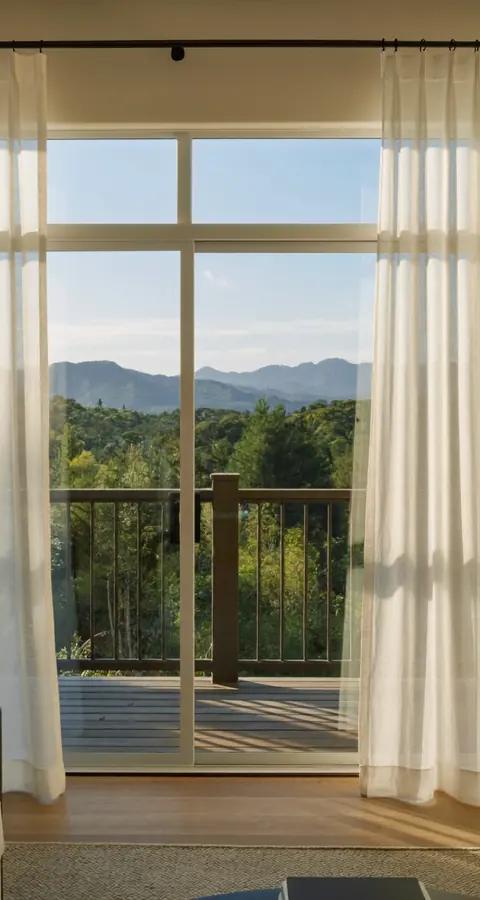 Soft vertical sheer shadings partly open at a sunny Denver patio door with a deck and foothills beyond