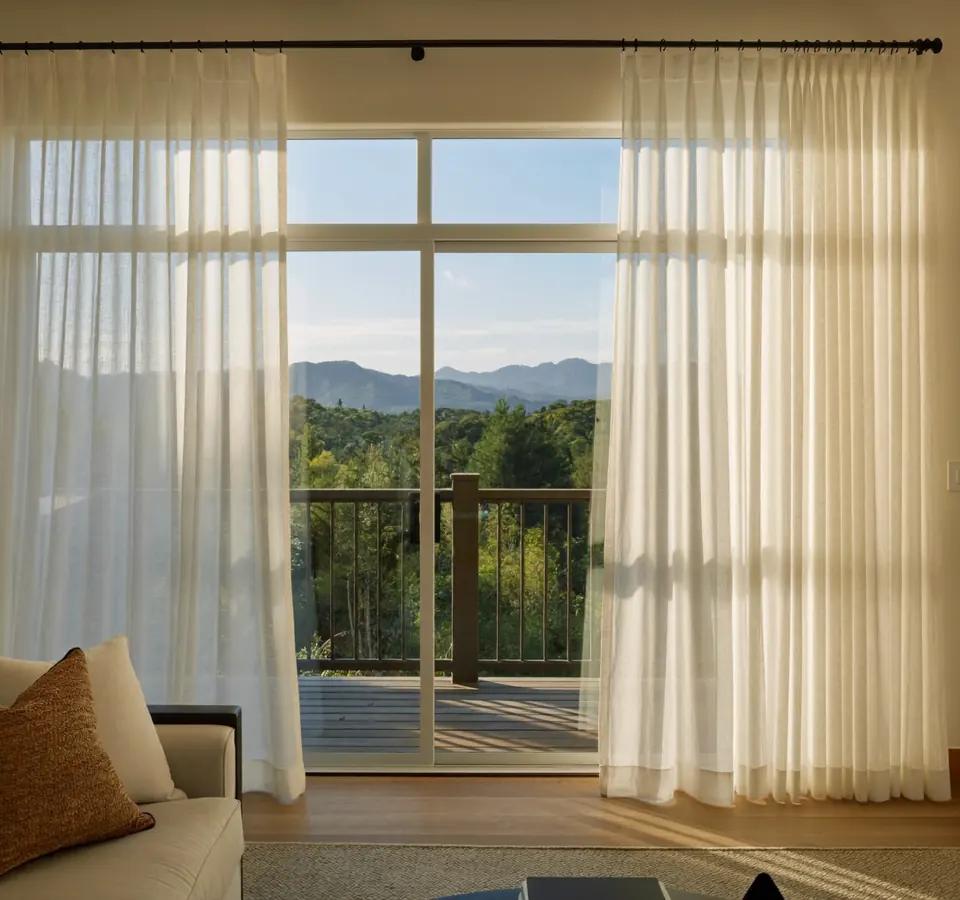 Soft vertical sheer shadings partly open at a sunny Denver patio door with a deck and foothills beyond