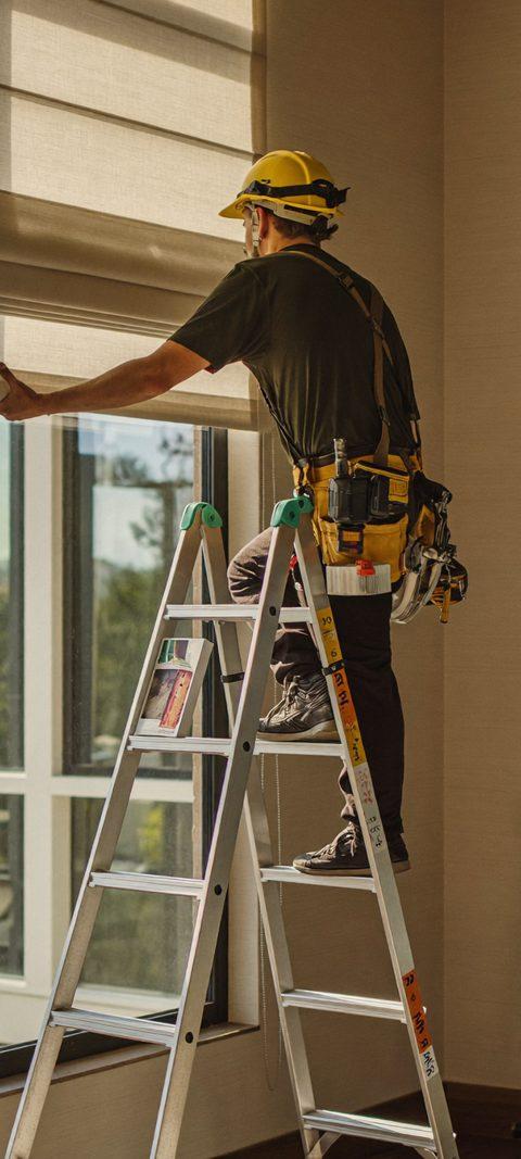Professional installer mounting a custom cellular shade bracket inside a window frame of a Denver home