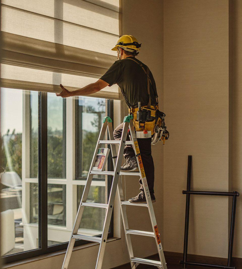Professional installer mounting a custom cellular shade bracket inside a window frame of a Denver home