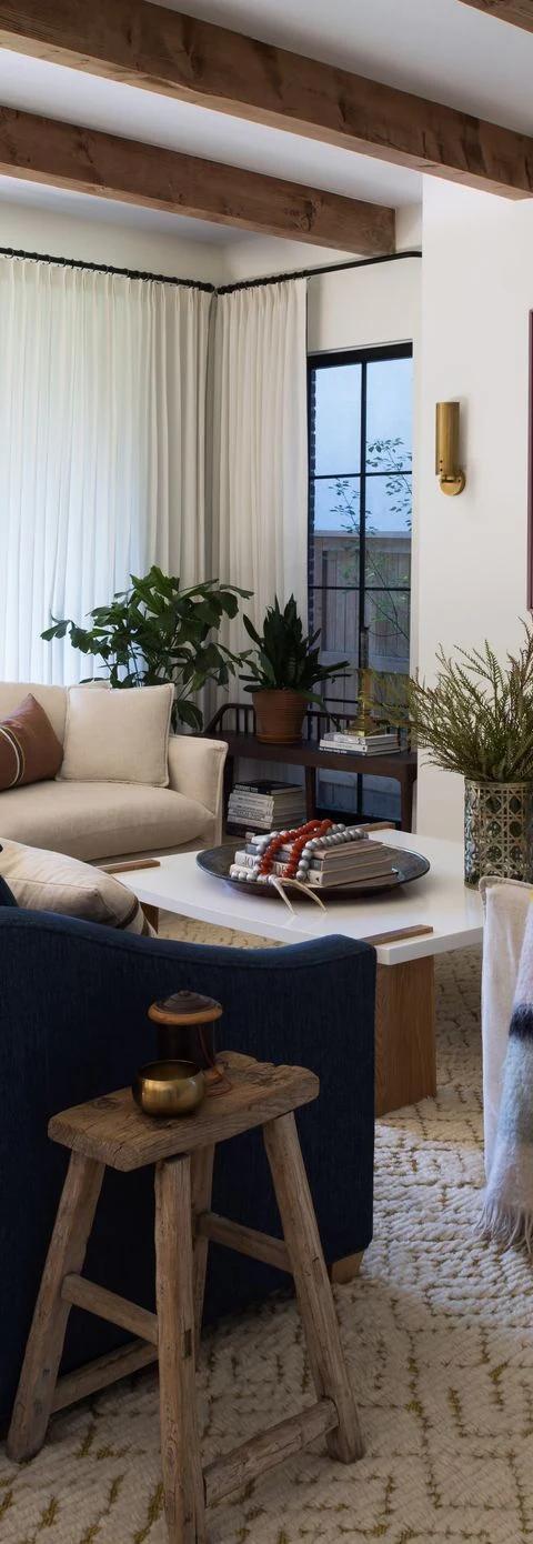 Blue upholstered chairs beneath dark drapery in a sunlit living room