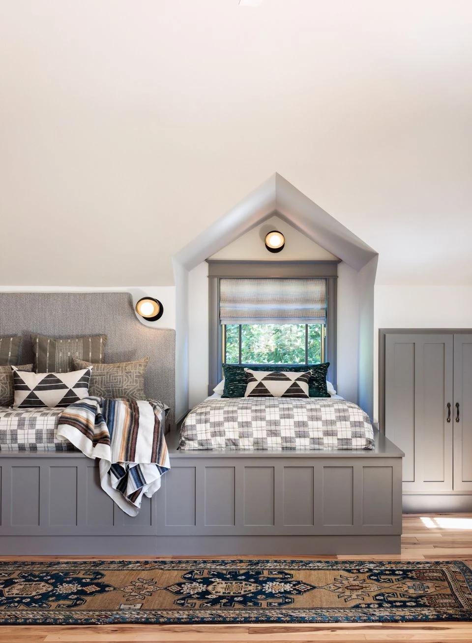 Layered bedroom window treatments surround twin beds in a bright interior