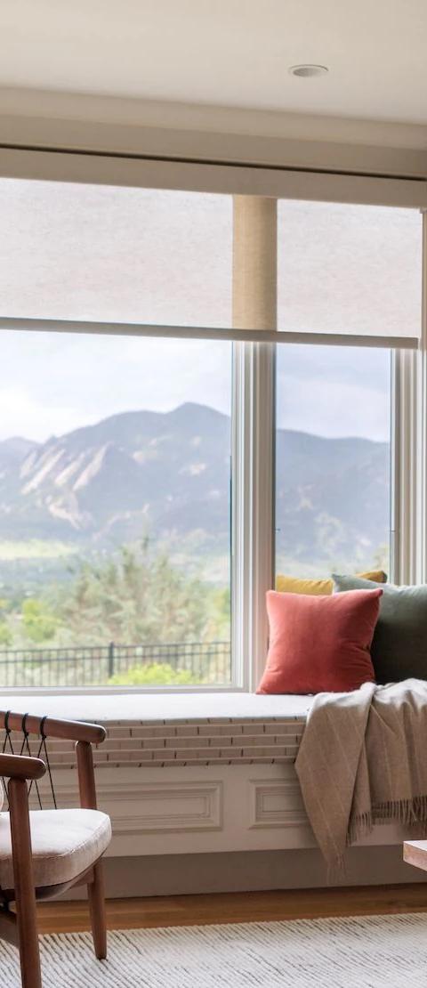 Fabric window shades frame a mountain view above a living room sofa