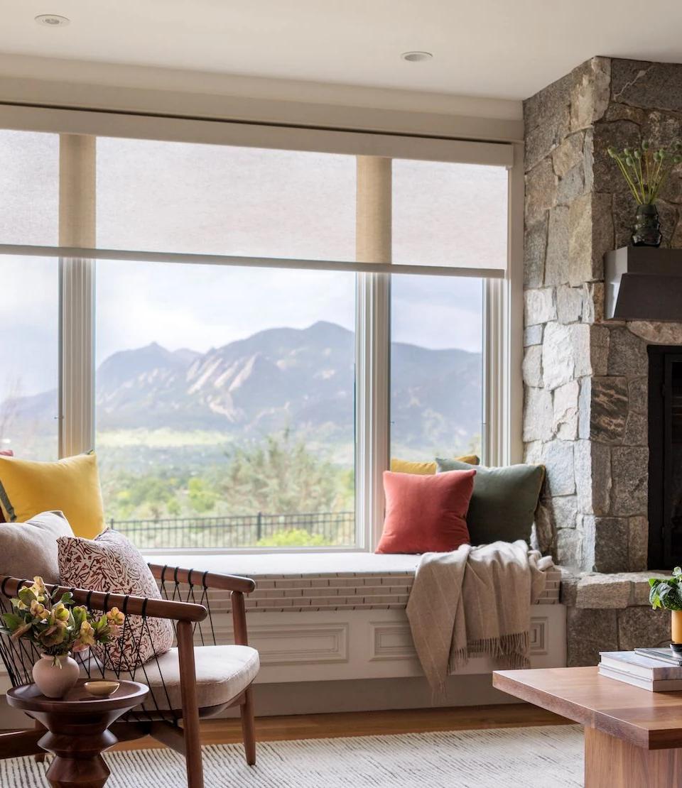 Fabric window shades frame a mountain view above a living room sofa