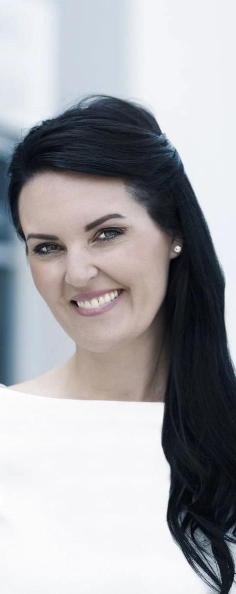 Portrait of Jessica Work smiling in a white top against a pale background