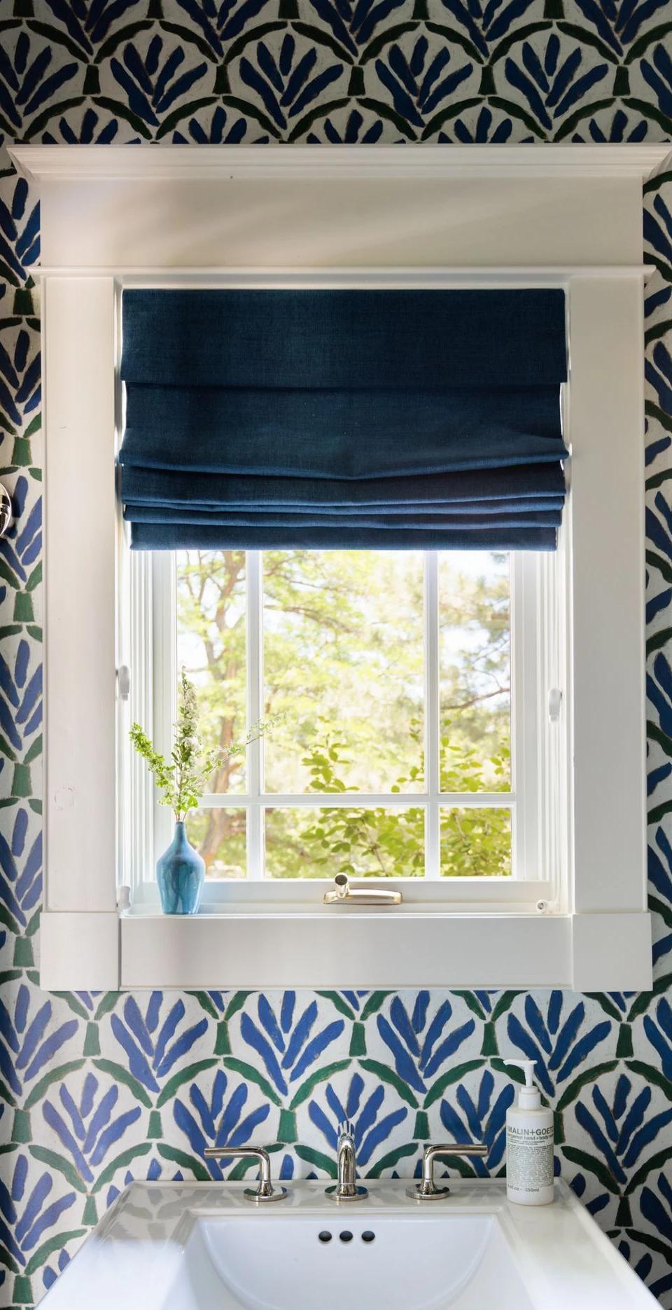 Dark Roman shade inside a small window surrounded by patterned wallpaper