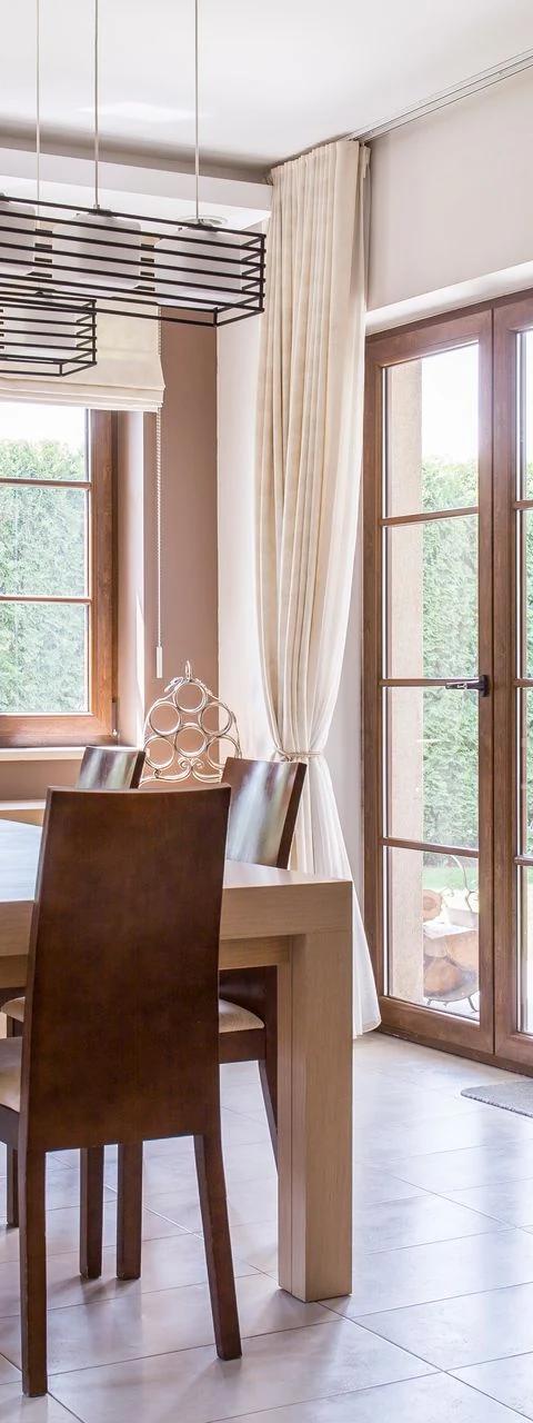 Roller shades hang beside a dining table and glass patio doors