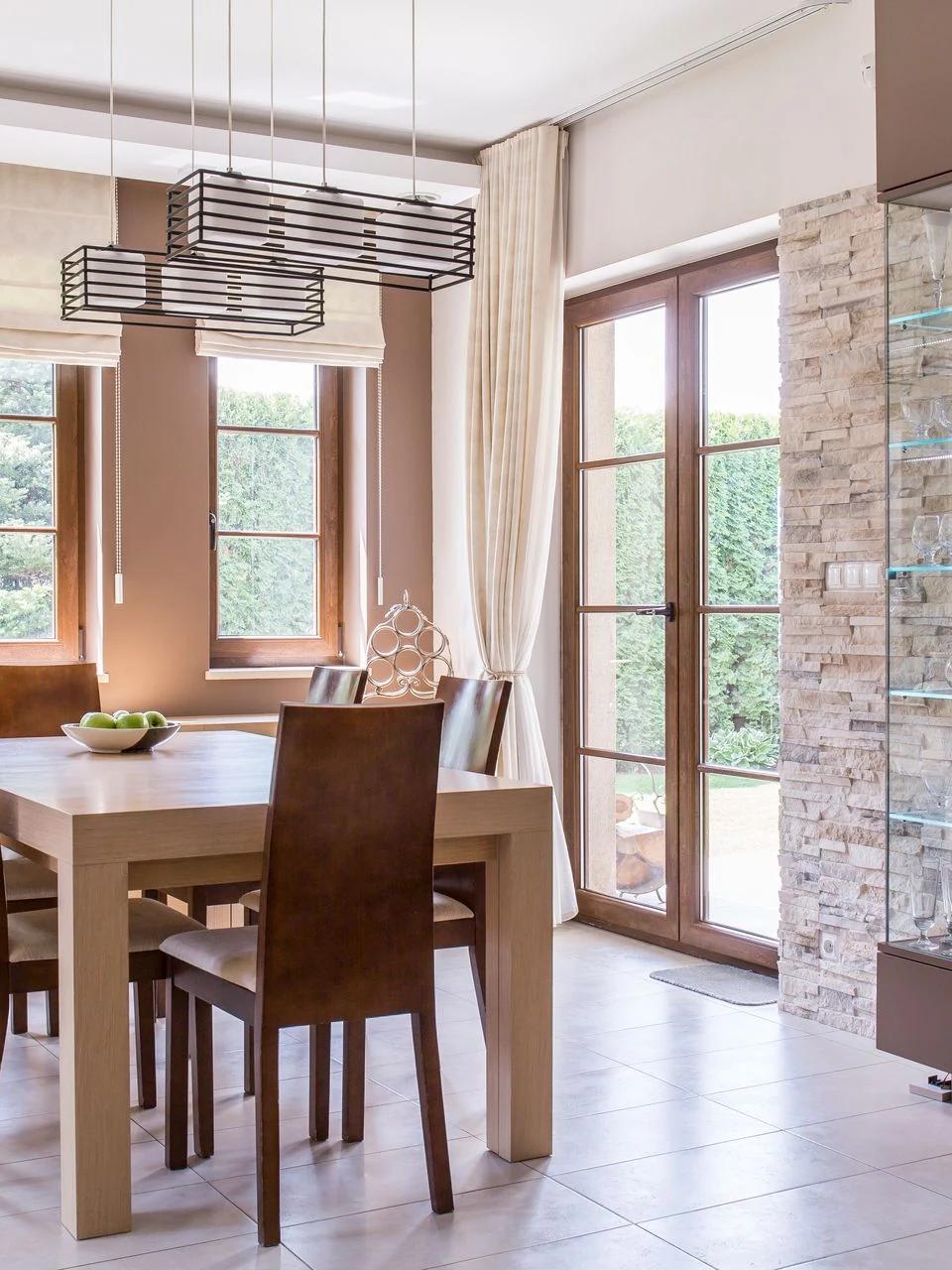 Roller shades hang beside a dining table and glass patio doors