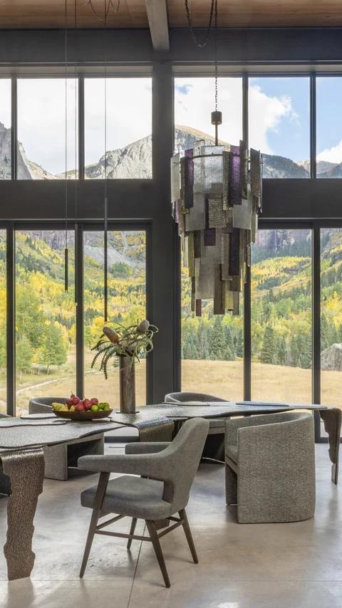 Floor to ceiling windows frame mountain scenery above a spacious seating area