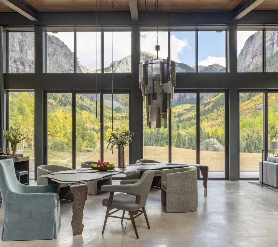 Floor to ceiling windows frame mountain scenery above a spacious seating area