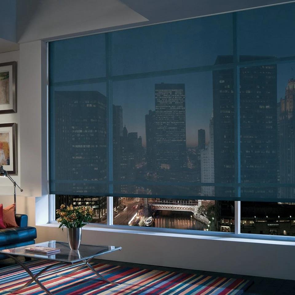 Dark solar shade covers a broad window overlooking a city skyline