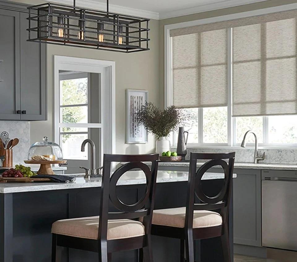 Kitchen windows with light coverings above a table and pale cabinetry